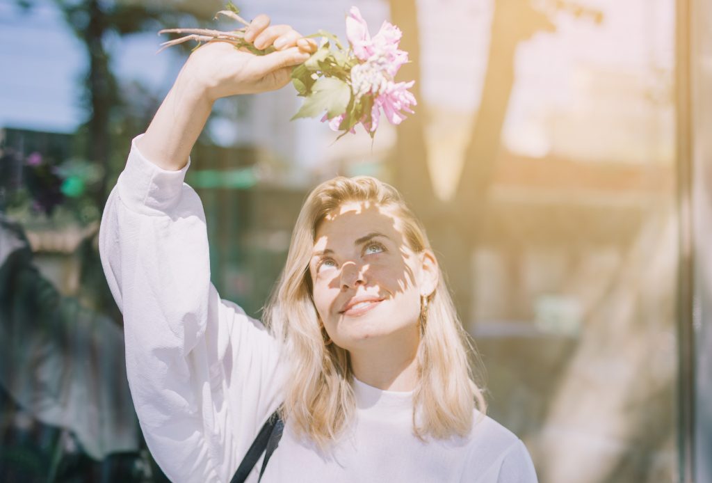 Junge Frau mit Blumen in der Sonne